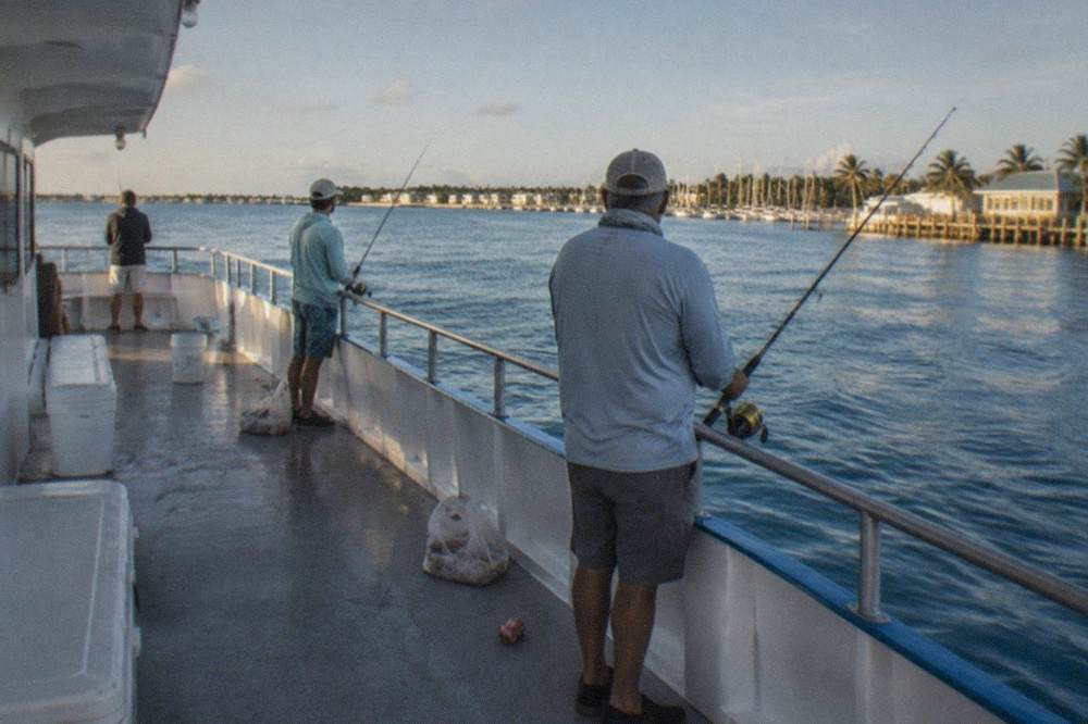 Anglers fishing from the deck of a party boat over calm blue water near Key West