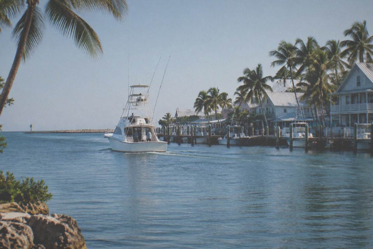 A sportfishing boat heading out of Key West harbor with a clear sky and calm blue water