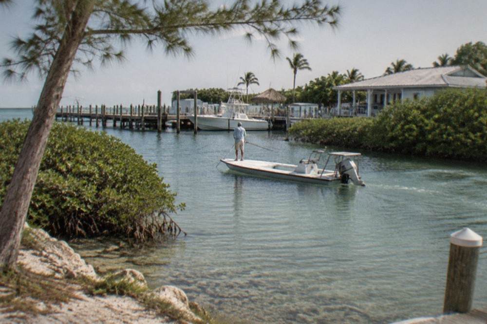 A flats skiff drifting over clear shallow water near mangrove keys