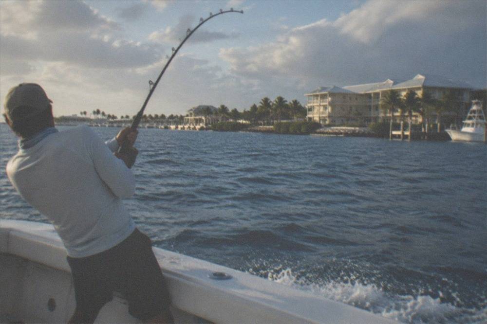 Angler fighting a fish from the deck of a charter boat in deep blue water