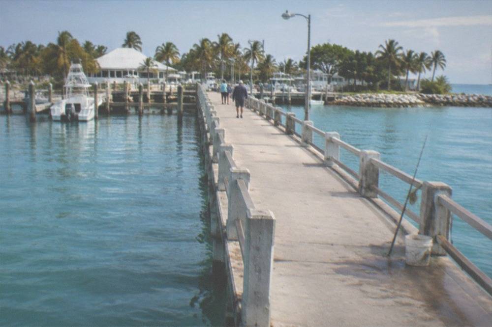 A long concrete pier extending over calm turquoise water toward the horizon
