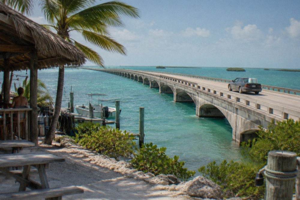 A car traveling over a long bridge with turquoise water on both sides in the Florida Keys