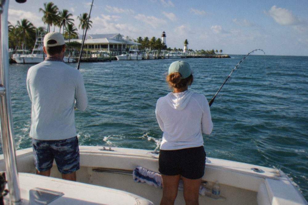 Anglers fishing from the stern of a small charter boat over open blue water near Key West