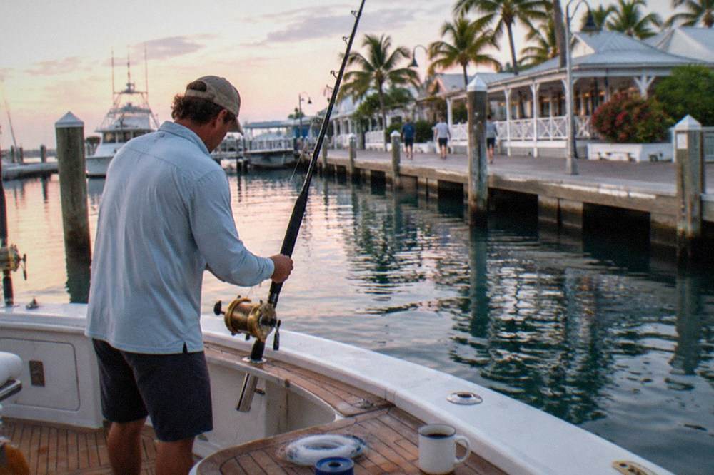 A charter mate rigging a fishing rod at the transom of a boat near Key West