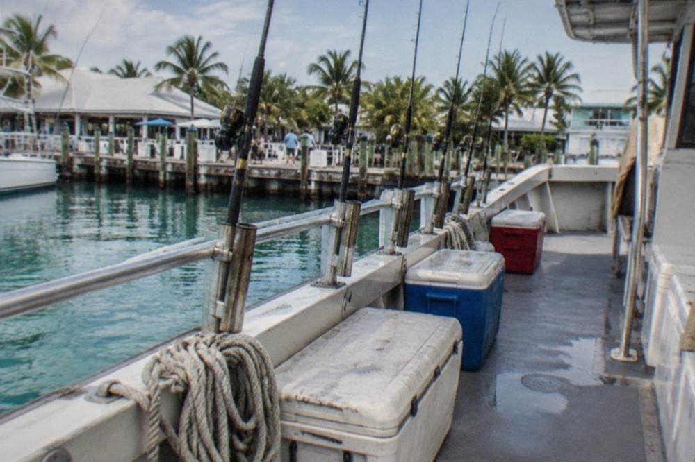 Party boat fishing deck with rod holders and coolers along the rail at a Key West dock
