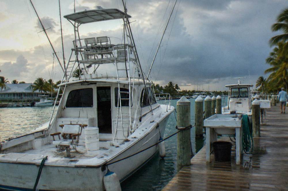 Large sportfishing boat with outriggers and a fighting chair tied up at a marina in Key West