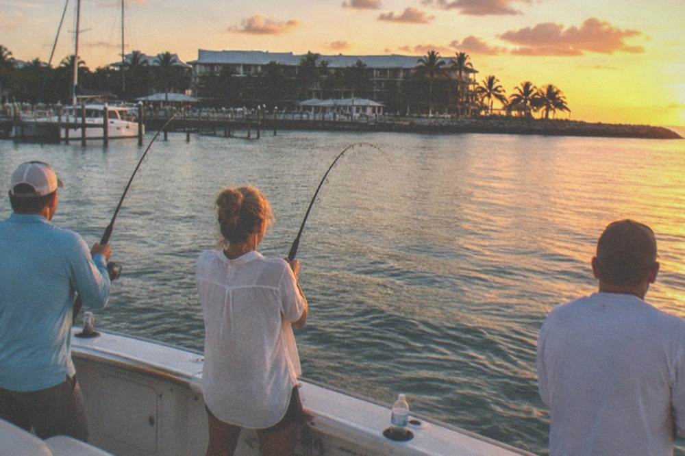 Anglers fishing from the deck of a boat as the sun drops toward the horizon off Key West