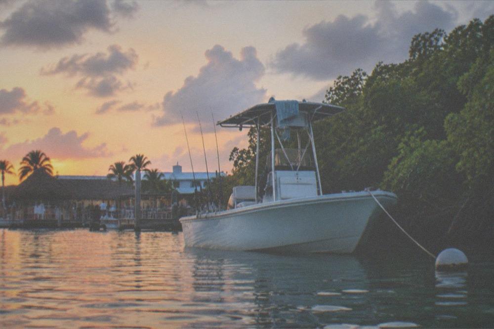 A bay boat anchored near a mangrove island with rods in holders waiting for a bite