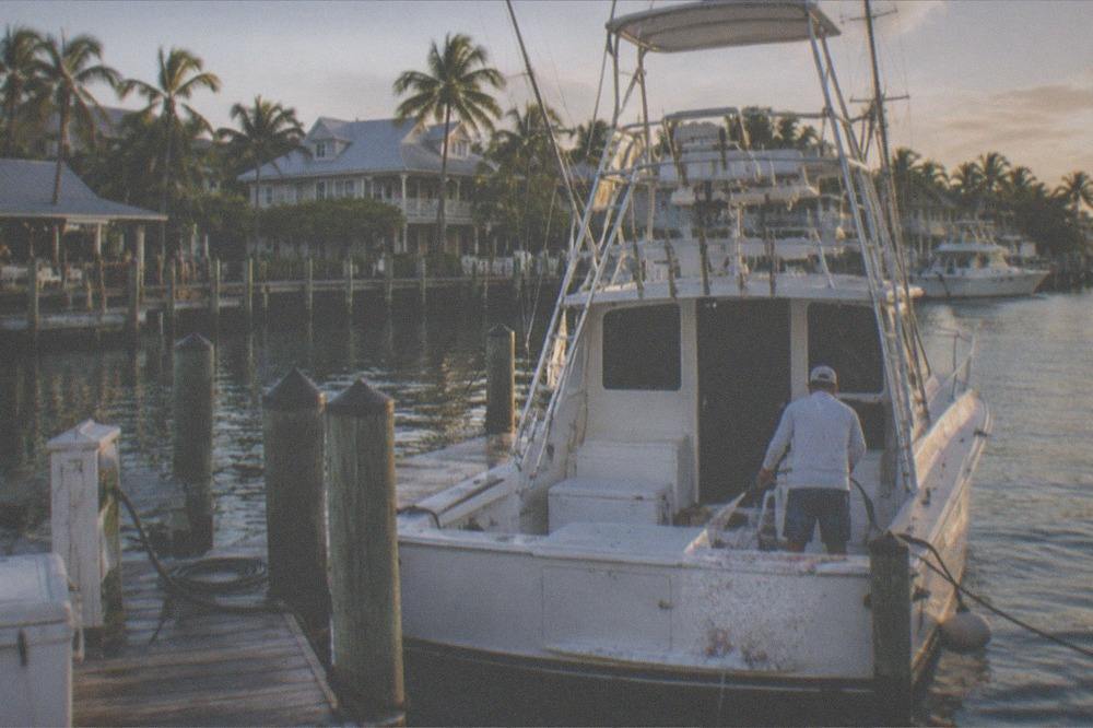 A sportfishing boat tied at a Key West charter dock in late afternoon light
