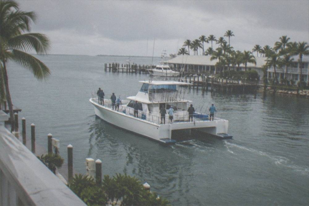 Large party fishing boat with anglers lined along the rail over reef water