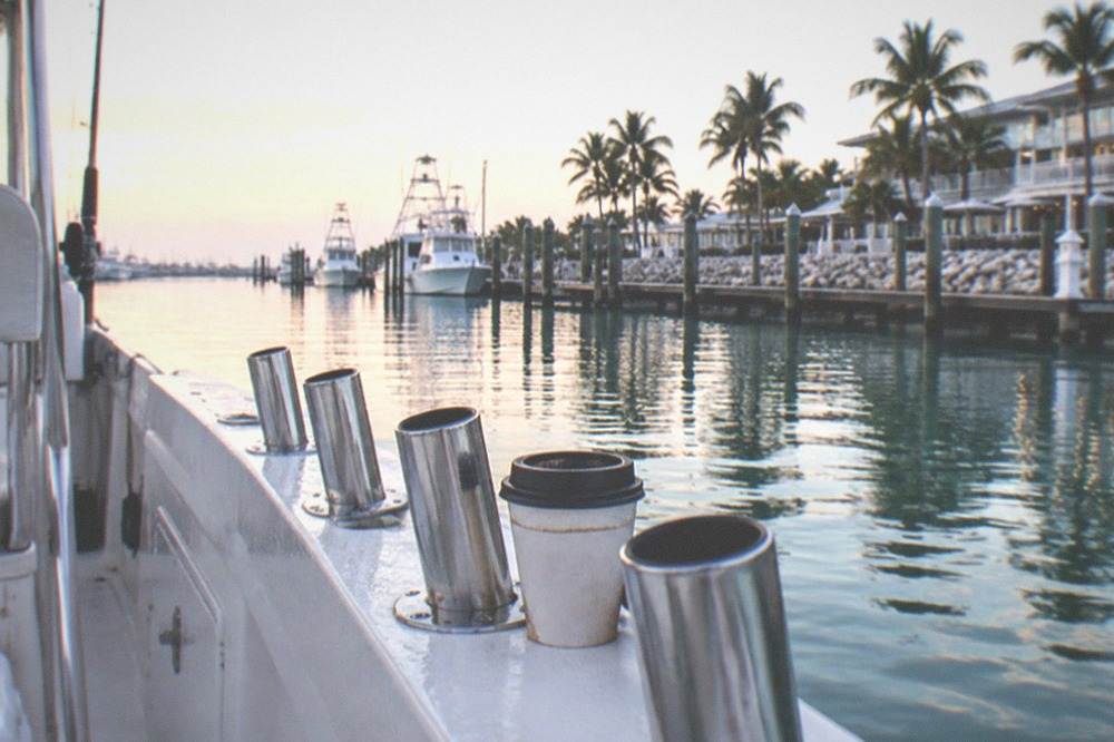 Fishing rods in holders along a charter boat gunwale at dawn