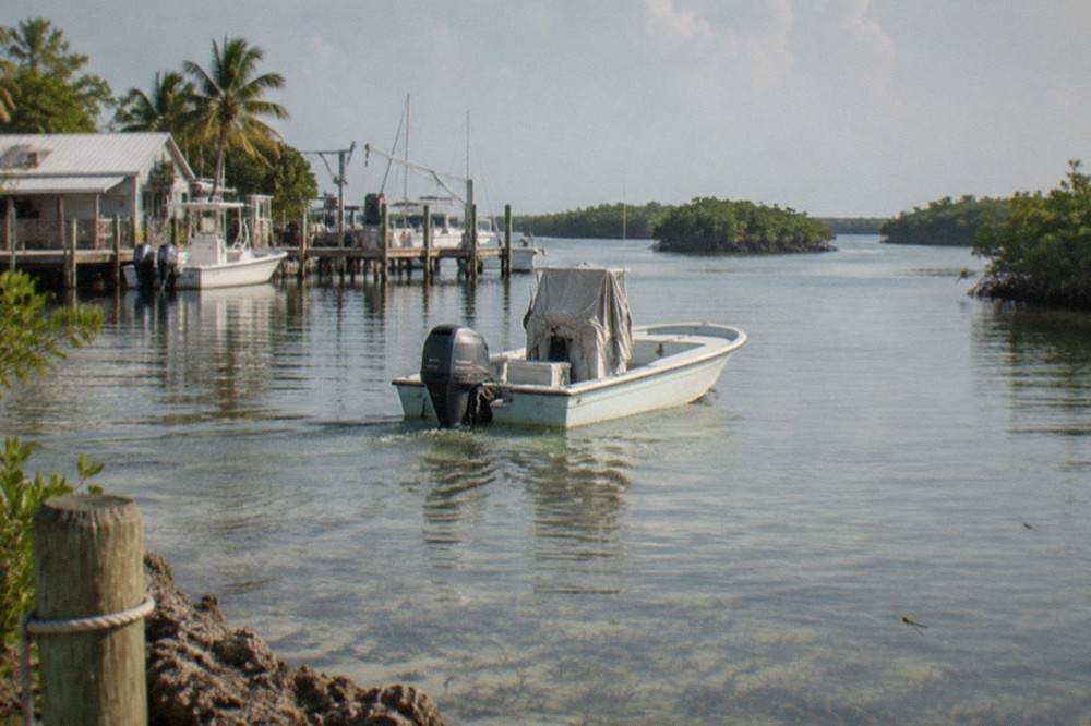 A bay boat idling over shallow turquoise backcountry water dotted with mangrove islands