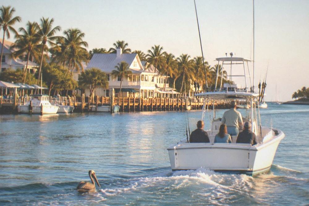 A charter boat crossing calm morning water toward the Key West harbor channel