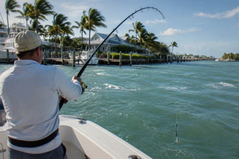 A fishing rod bent over the rail of a boat above clear reef water