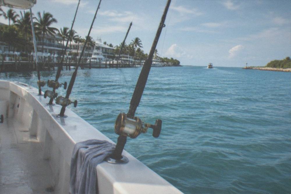 Fishing rods secured in holders along the rail of a boat with open blue water on the horizon