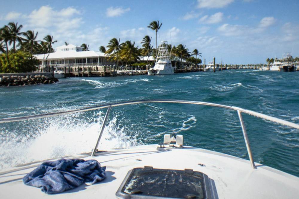 Fishing boat crossing choppy blue water with spray at the bow