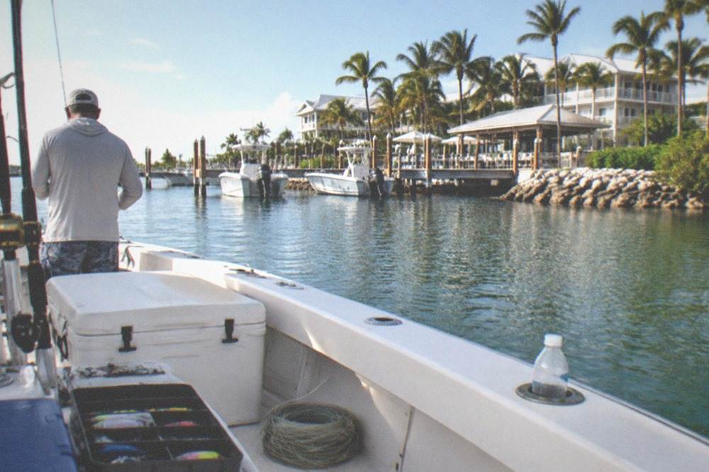 Anglers on a fishing boat deck with coolers and tackle on a calm sea day