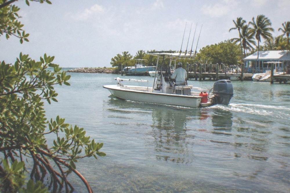 A bay boat rigged with rods running across calm backcountry water