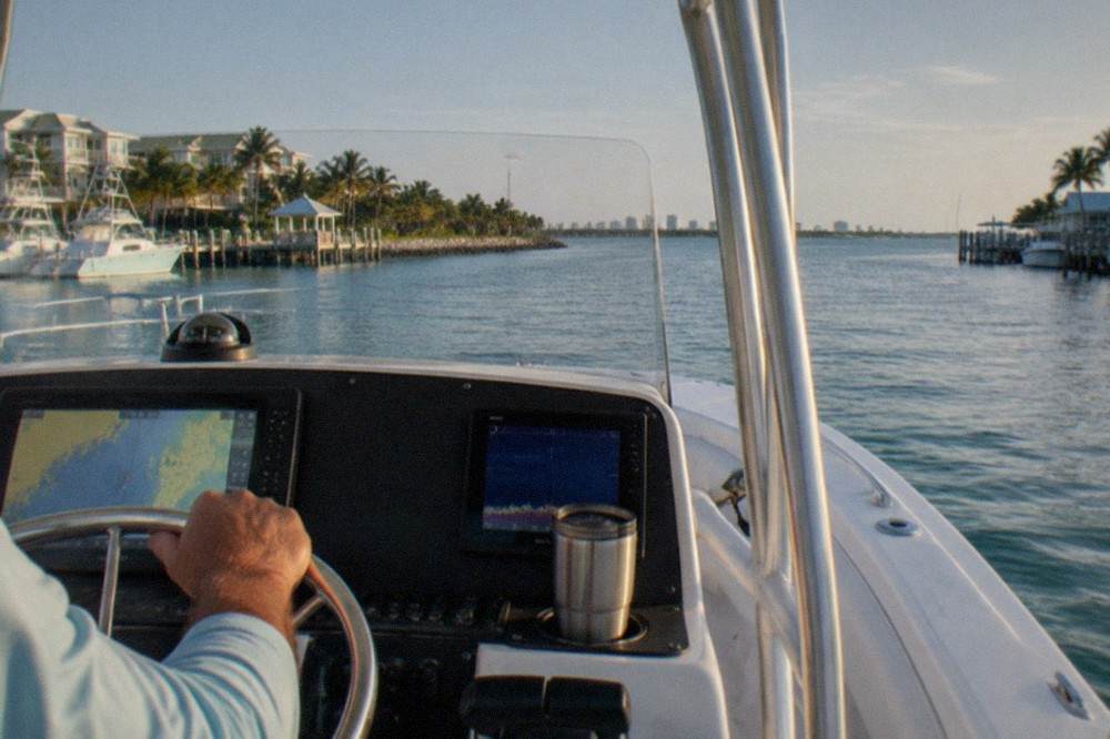 Charter captain at the helm of a sportfishing boat steering through calm blue water off Key West