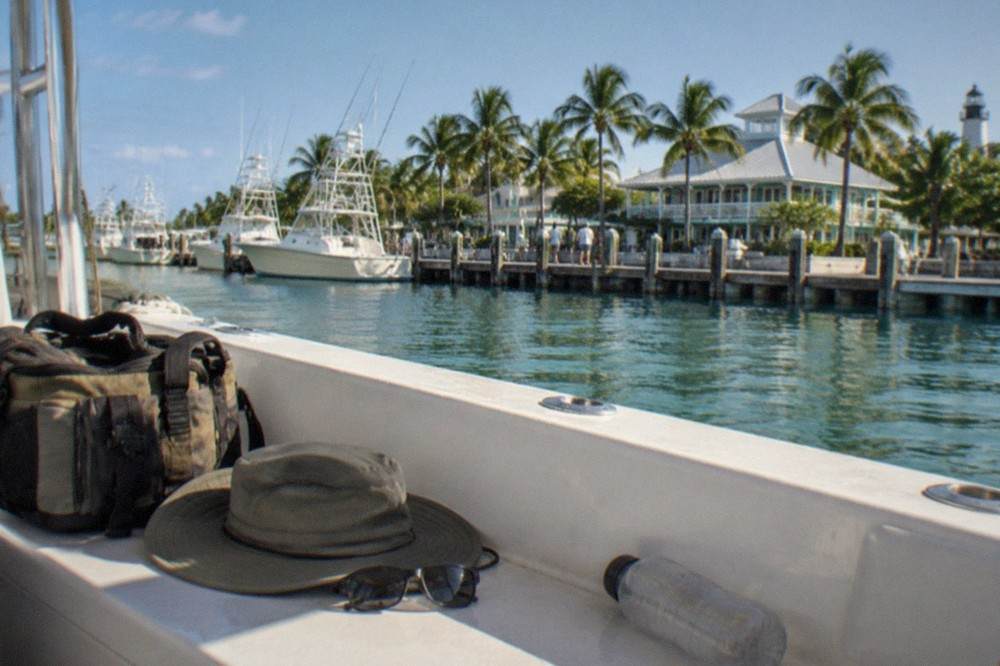 A tackle bag, hat and sunglasses resting on a charter boat bench at a Key West marina