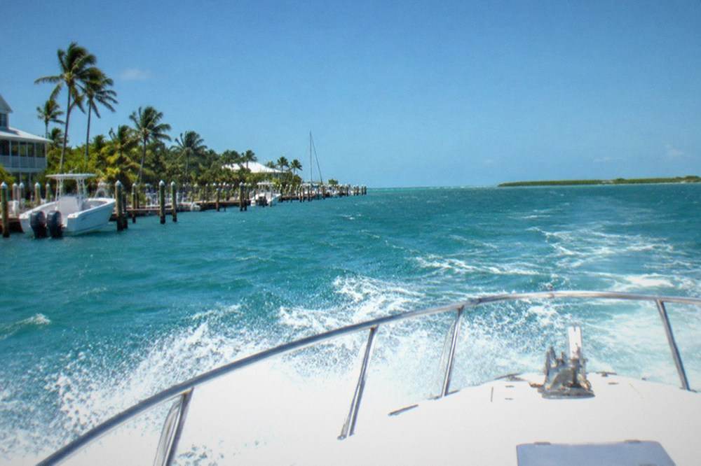 An offshore charter boat running across open blue water with spray over the bow