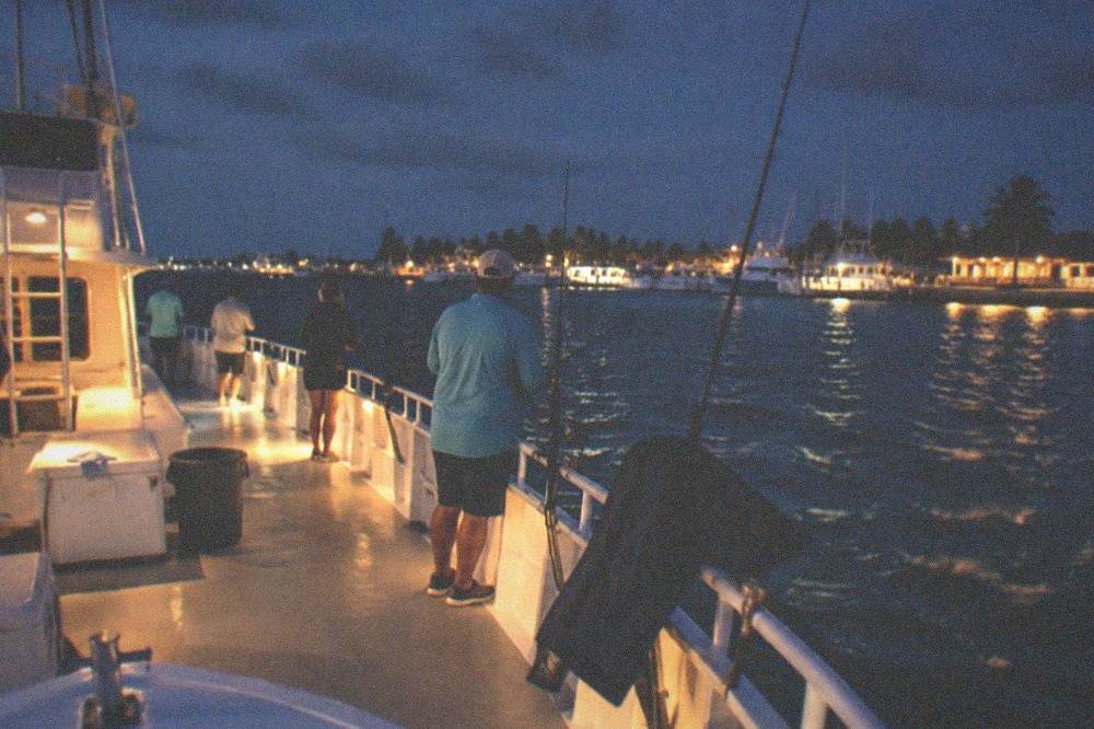 Anglers lined along the rail of a large party boat fishing over a reef