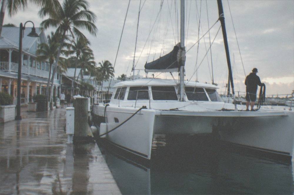 A large catamaran at a harbor dock near Old Town buildings in early morning light