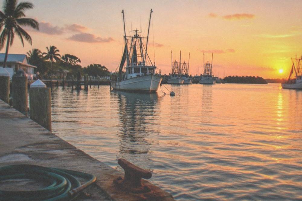 A sunset over calm water with boats at anchor near a Key West shoreline